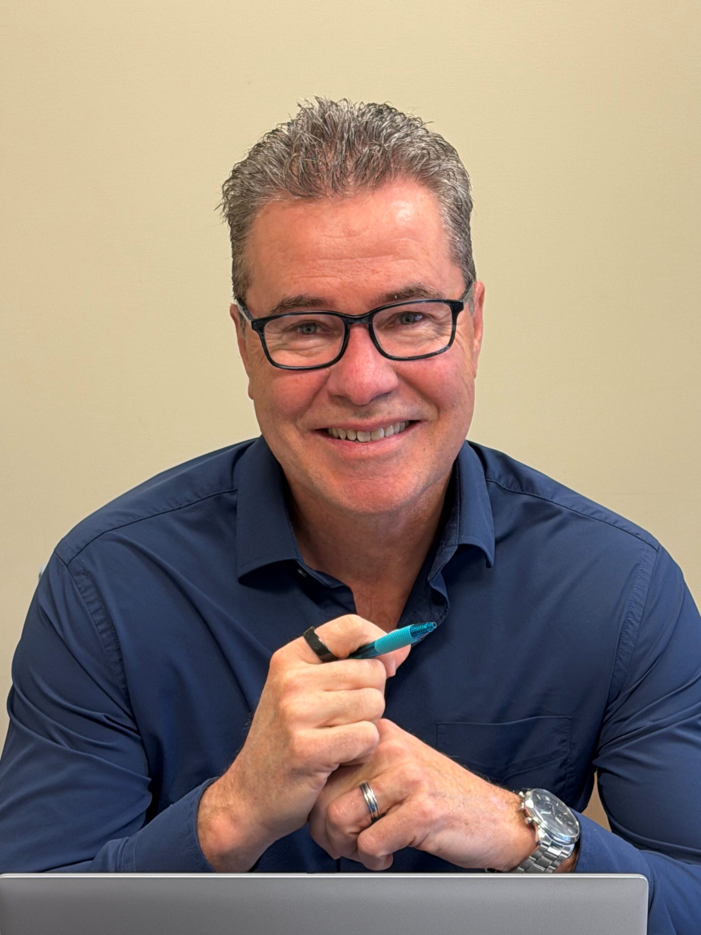 Smiling man with glasses holding a pen