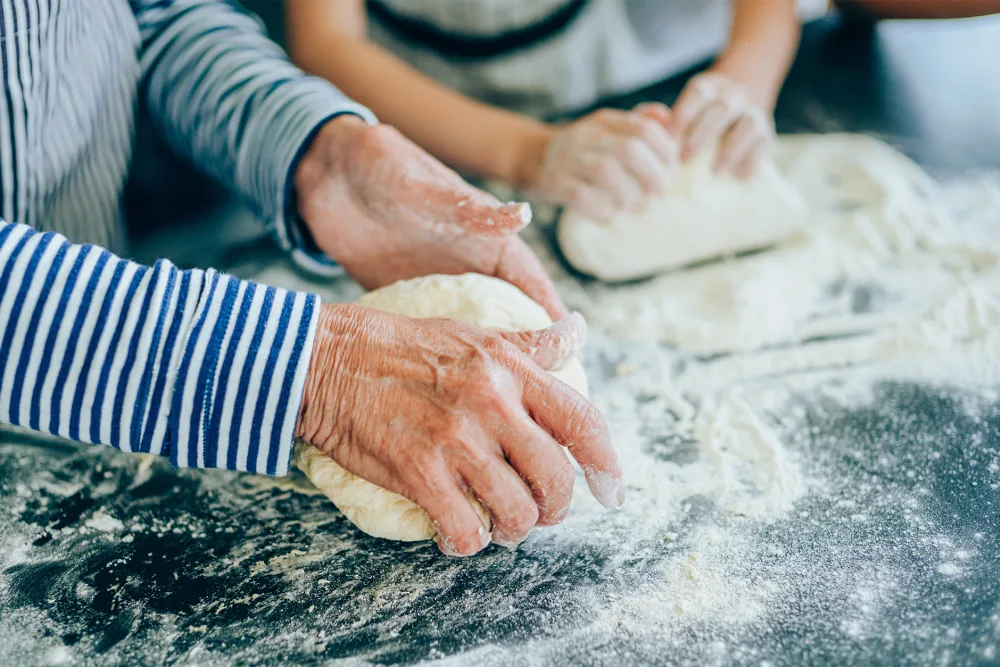 Grandparent and child kneading dough together