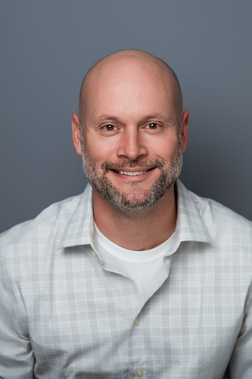 Smiling bald man with beard against gray background