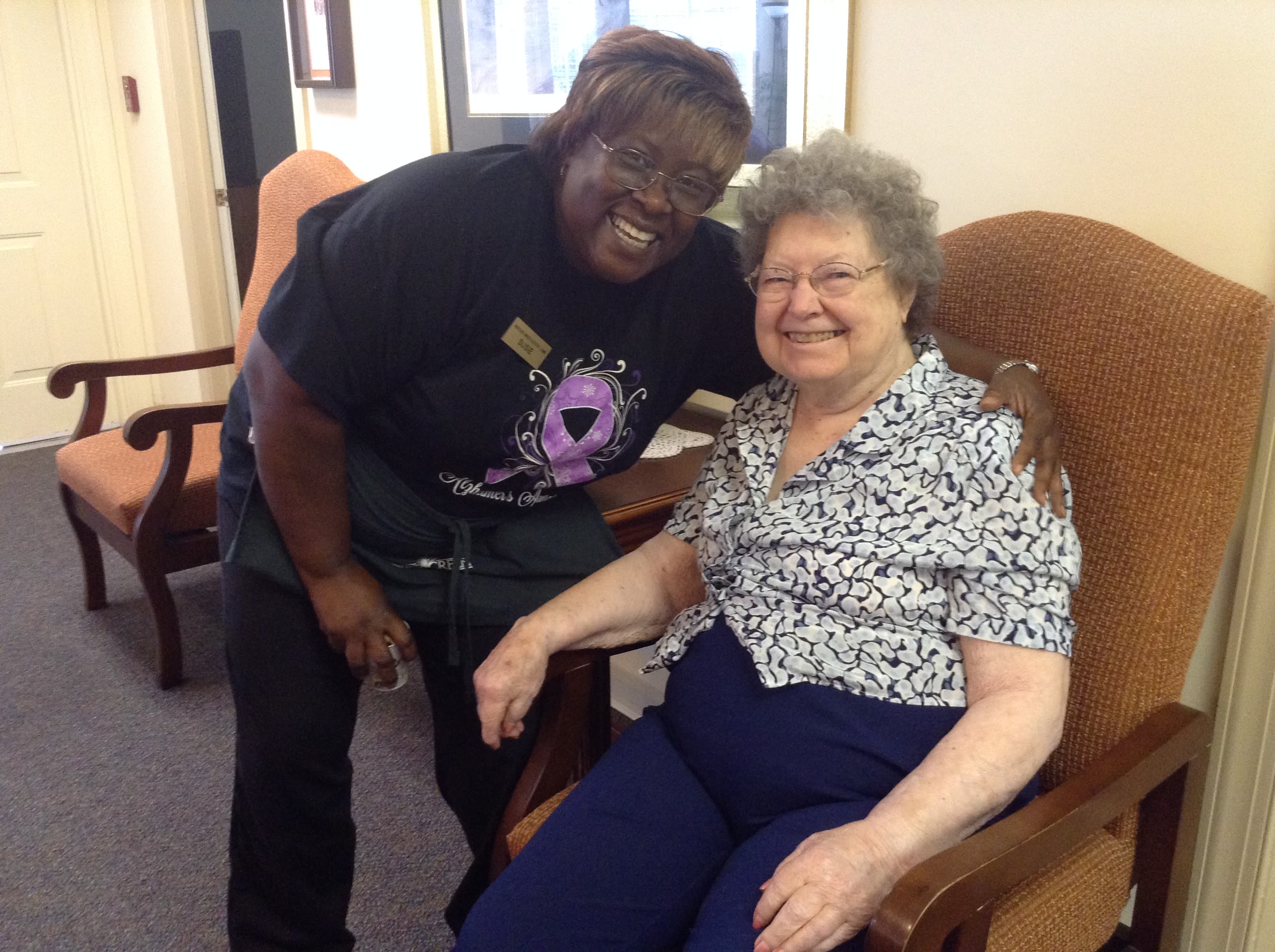 Caregiver and elderly woman smiling together indoors