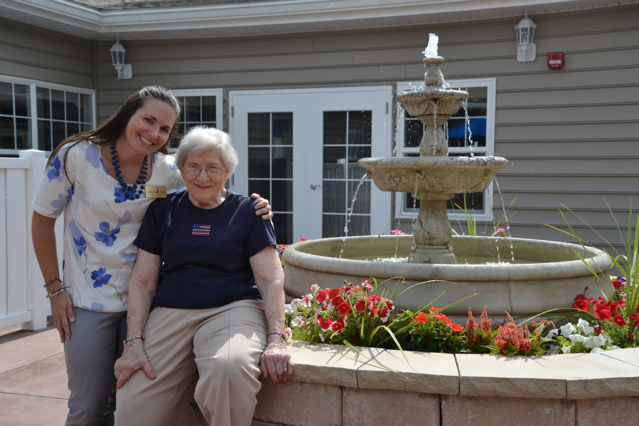 Two women smiling by outdoor garden fountain