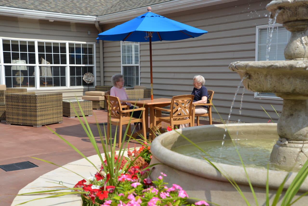 Two elderly women chatting at patio table